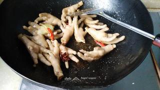 Braised Chicken Feet step 8: Add star anise, dried chilies, and ginger slices. Stir-fry until fragrant.
