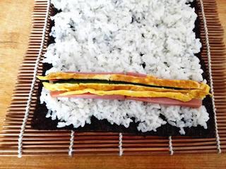 Ham and Cucumber Sushi Rolls step 6: Arrange the cucumber, ham, and egg strips in a line near one edge of the rice.
