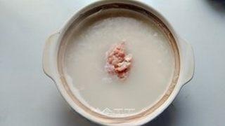Century Egg and Pork Congee step 6: Add the marinated pork to the congee and bring it back to a gentle boil. Simmer