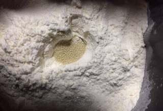 Milk Bread Caterpillar Rolls step 2: Make a small well in the flour, add the yeast, and cover it lightly with flour.
