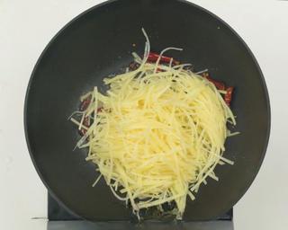 Hot and Sour Shredded Potatoes step 6: Add the potato strips, scallion, and garlic. Stir-fry over high heat until evenl