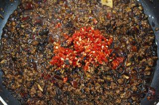 Spicy Beef Chili Crisp step 6: Add additional oil if needed, then stir in the minced garlic and ginger. Cook un