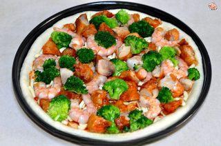 Homemade Shrimp and Chicken Pizza step 8: Arrange the cooked chicken, shrimp, and broccoli evenly across the pizza.