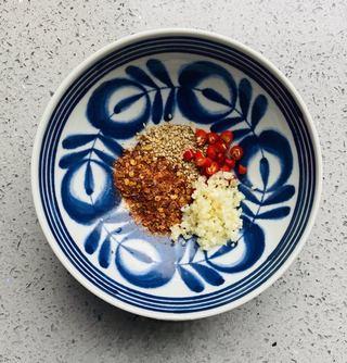 Sichuan Hot and Sour Vermicelli step 5: Place garlic, chopped chilies, and sesame seeds in a serving bowl.