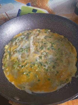 Easy Scallion Egg Pancakes step 5: Crack an egg directly onto the pancake and spread it evenly across the surface w