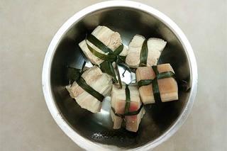 Red-Braised Pork Belly step 5: Arrange green onion segments and ginger slices on the bottom of a clay pot or he