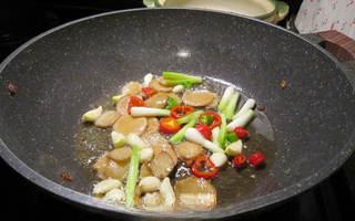 Clay Pot Basil Chicken step 5: Add the garlic cloves, scallion whites, and chili rings. Stir-fry briefly.